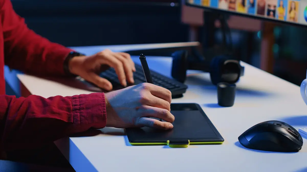 Graphic designer using stylus on touchscreen graphic tablet to modify images close up