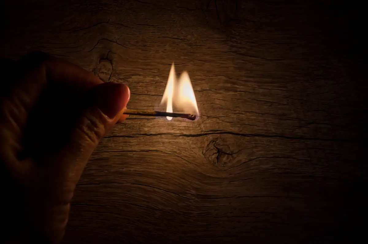 Lit match in hand  on dark  background