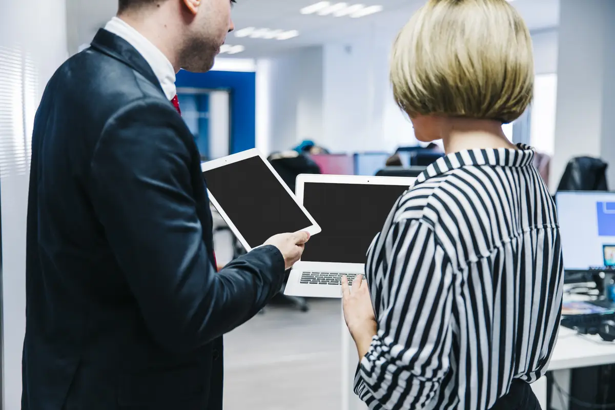 Stylish coworkers showing gadgets to each other