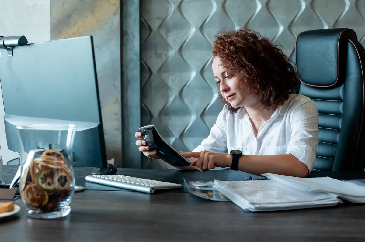 Controle cambial do faturamento em dólar para brasileiros nos EUA 1 Portrait of young office worker woman sitting at office desk using calculator to calculate something with serious confident expression on face working in office