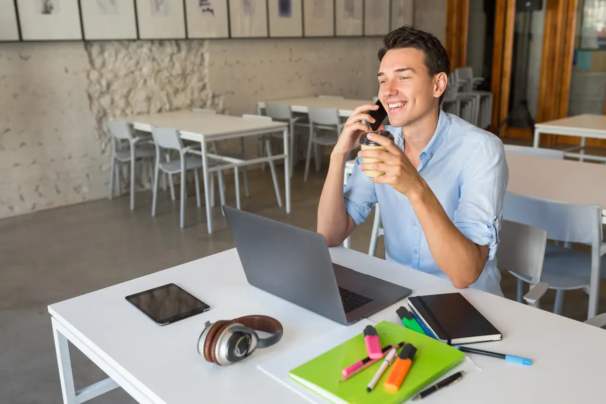 Laughing young attractive man busy talking on smart phone