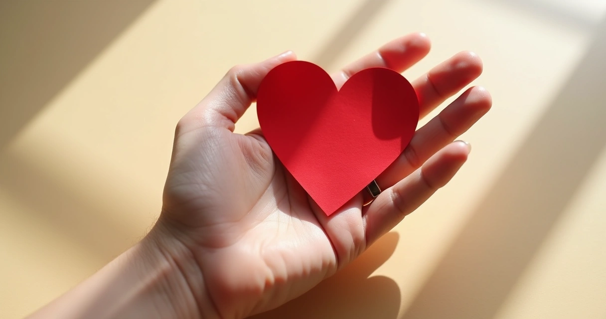 Mano abrazando un corazón de papel rojo 