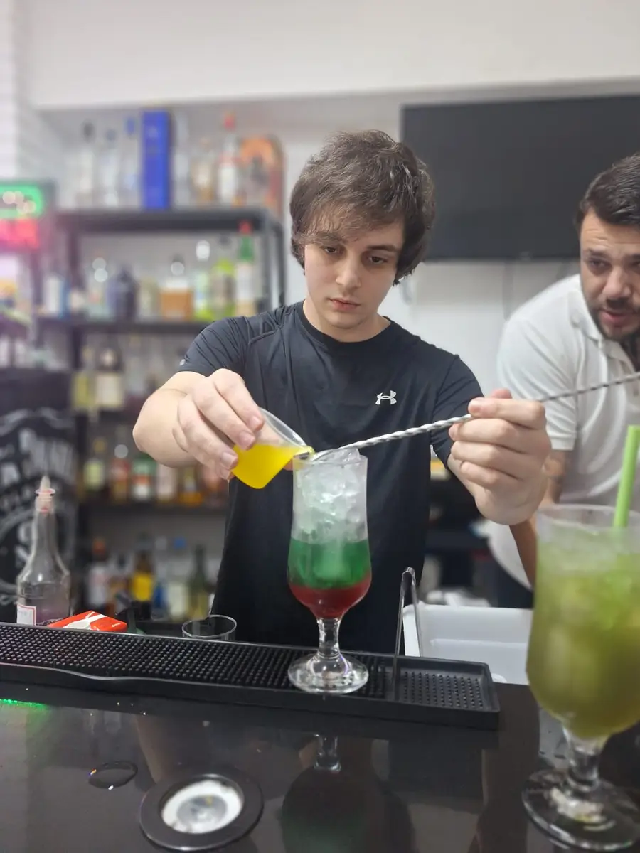 Aluno preparando coquetel colorido com gelo em escola de bartenders