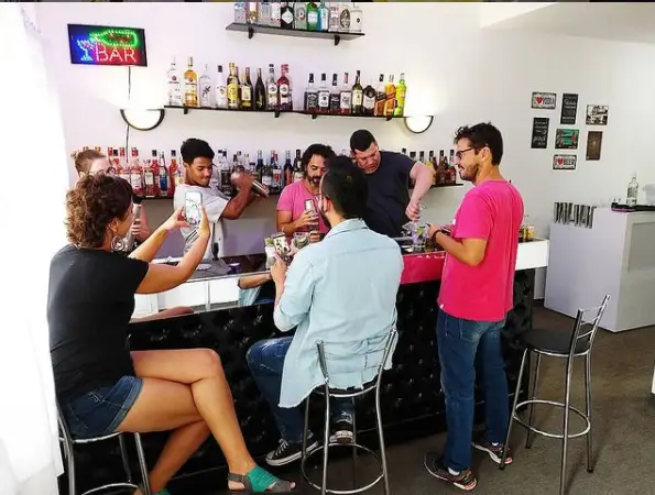 Grupo em aula prática de bartender em bar com bebidas e coquetéis