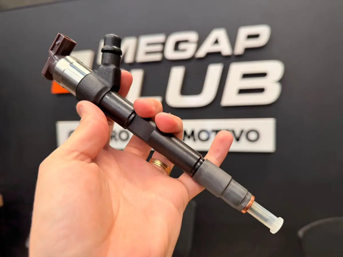 Mão segurando um bico injetor automotivo preto com detalhes metálicos em frente a um painel com logo Megap Lub