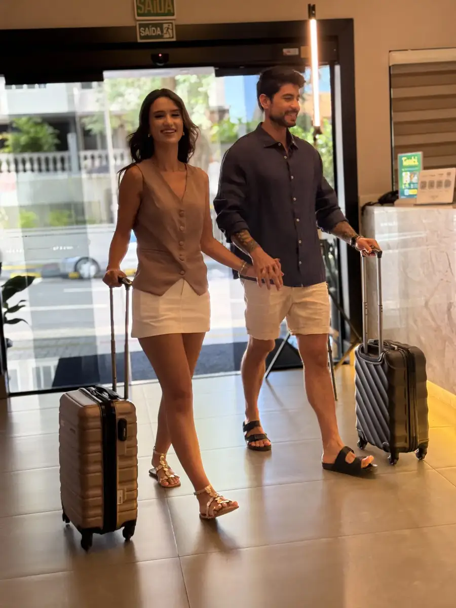 Casal com malas de rodinhas andando na recepção do hotel Tarobá