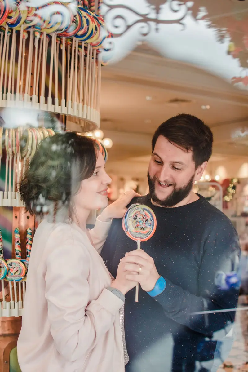 Casal segurando pirulito colorido com estampa da Disney em loja de doces