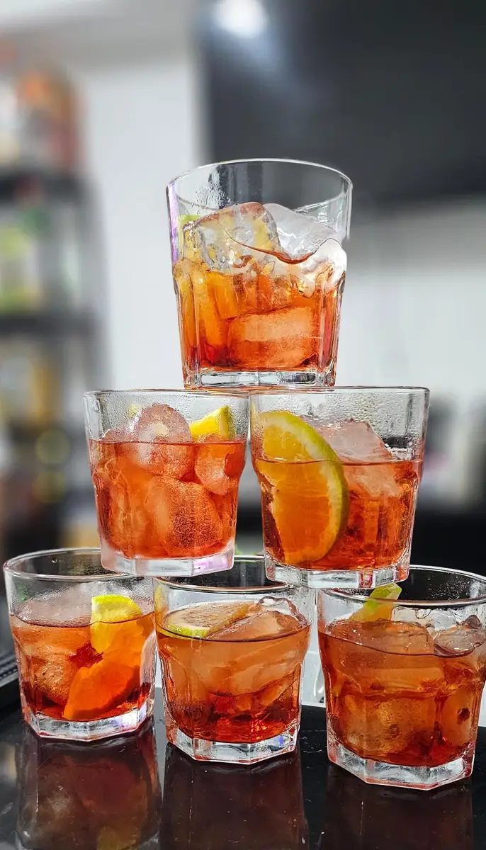 Seis copos de coquetel com vermute e fatias de laranja, arranjados em formato de pirâmide