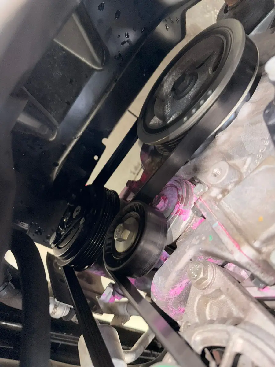 Correia de transmissão e polias no motor de um carro com marcas em tinta rosa