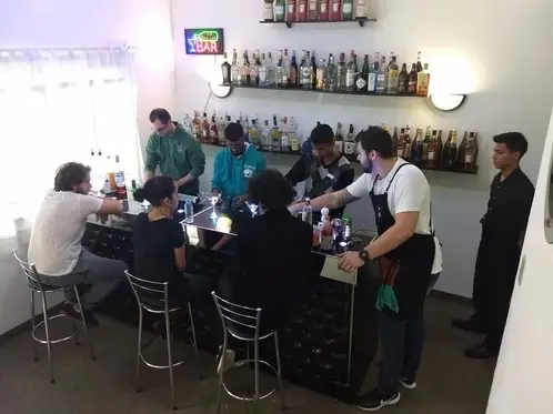 Turma de alunos em curso de bartender na LuxBar praticando coquetelaria no bar