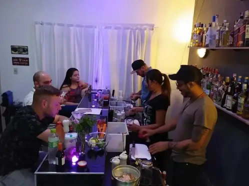 Grupo de pessoas praticando bartending em bar interno com iluminação aconchegante