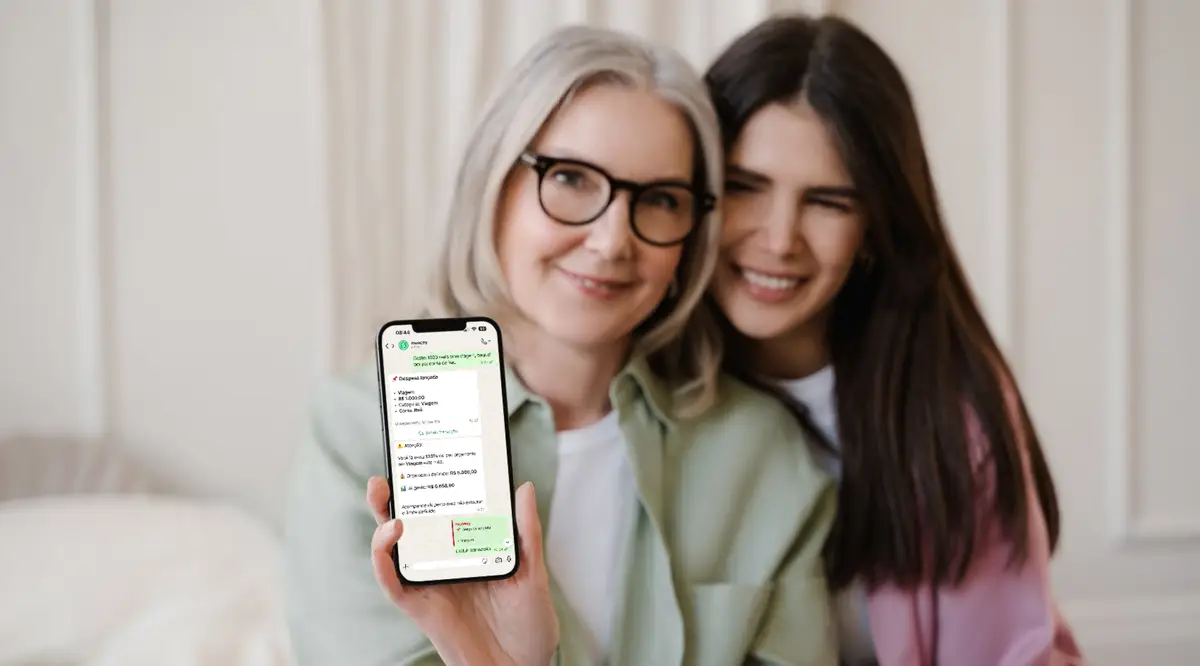 Duas mulheres sorrindo mostram um celular com a tela do aplicativo moneey aberta.