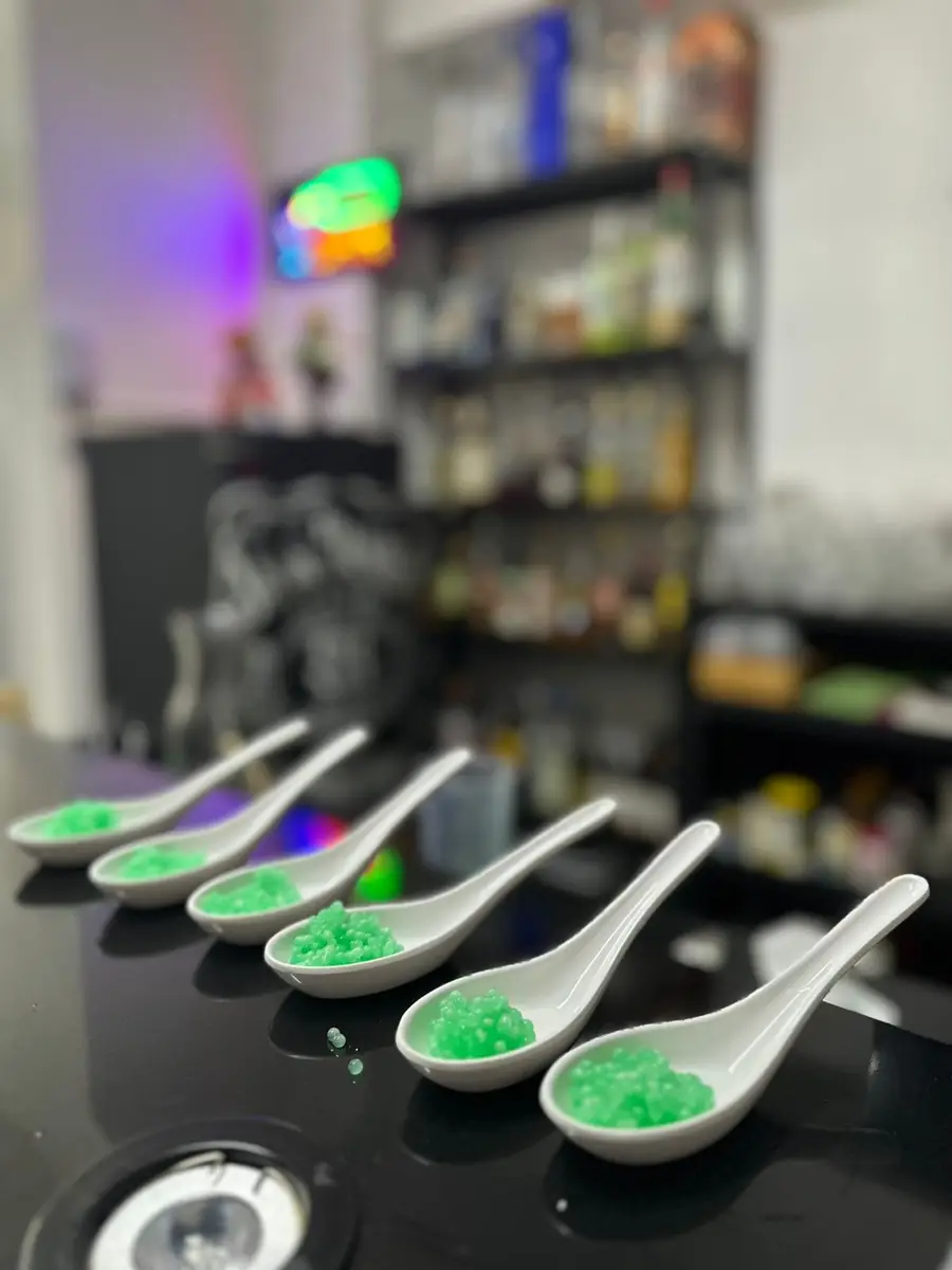 Colheres brancas alinhadas com esferas verdes em superfície preta