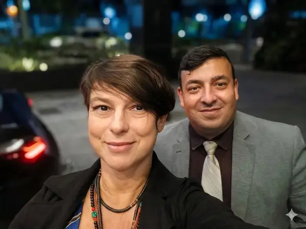 Mulher e homem de terno sorrindo em ambiente externo à noite