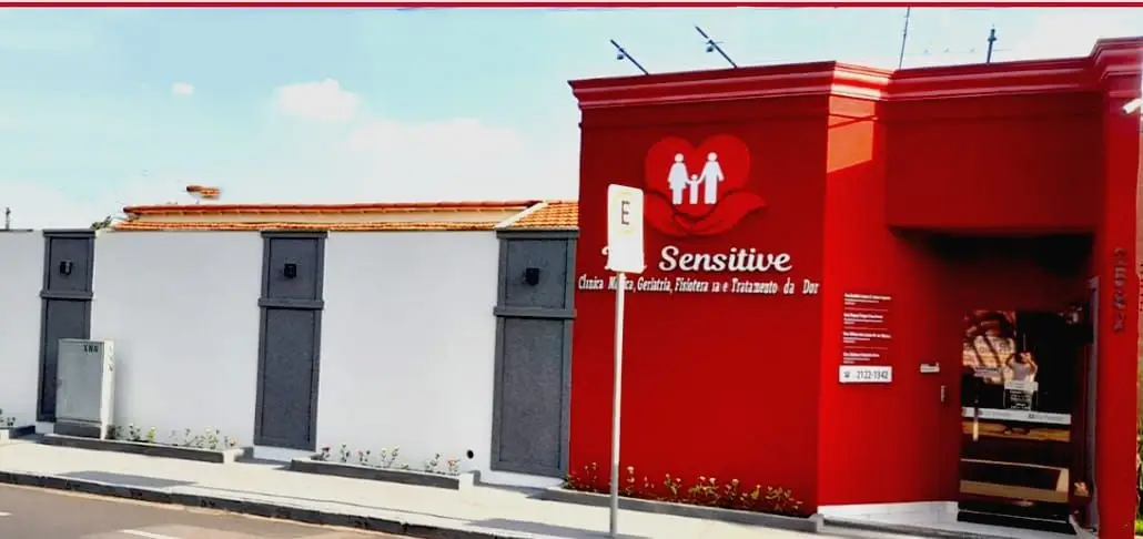 Fachada da clínica L’a Sensitive em Mirassol com parede vermelha e branca e logo com coração e figuras humanas