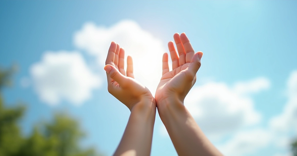 Hands lifted up in prayer towards an expansive bright blue sky with soft clouds 