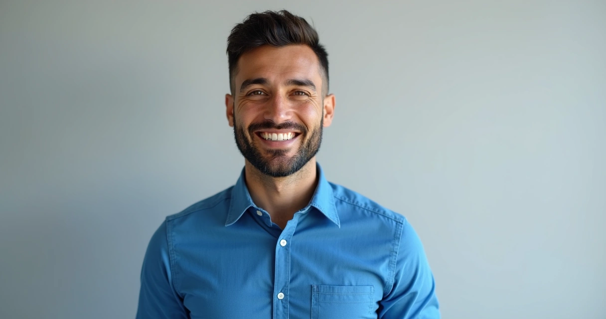 Homem com roupa social sorrindo em fundo neutro 