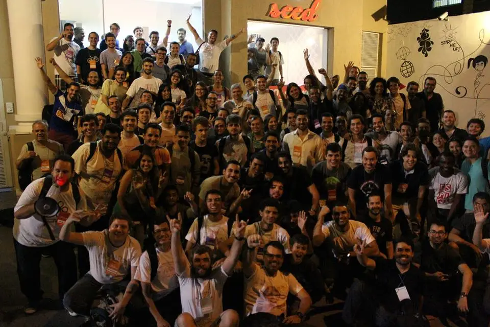 Grande grupo de pessoas reunidas em frente a um prédio à noite, em evento de tecnologia