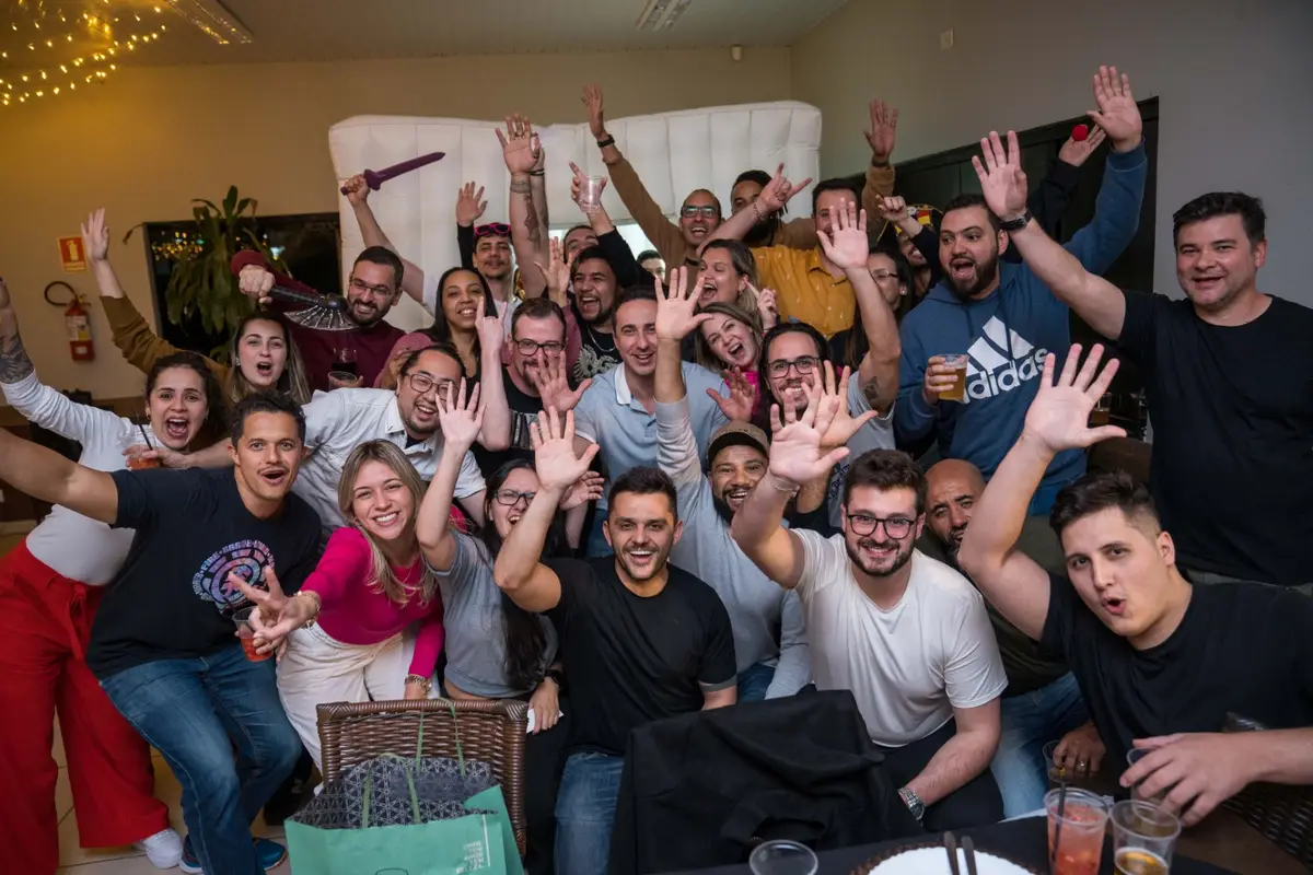 Grupo de pessoas animadas fazendo gesto de mãos para cima em celebração