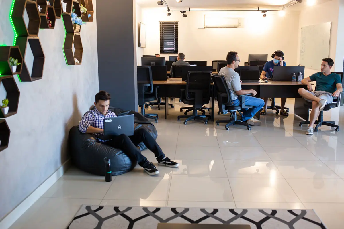 Homem trabalhando em laptop sentado em puff preto em escritório moderno