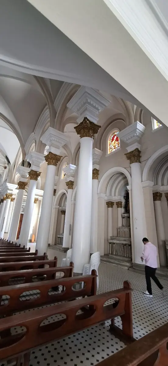 Interior de igreja com colunas brancas e detalhes dourados