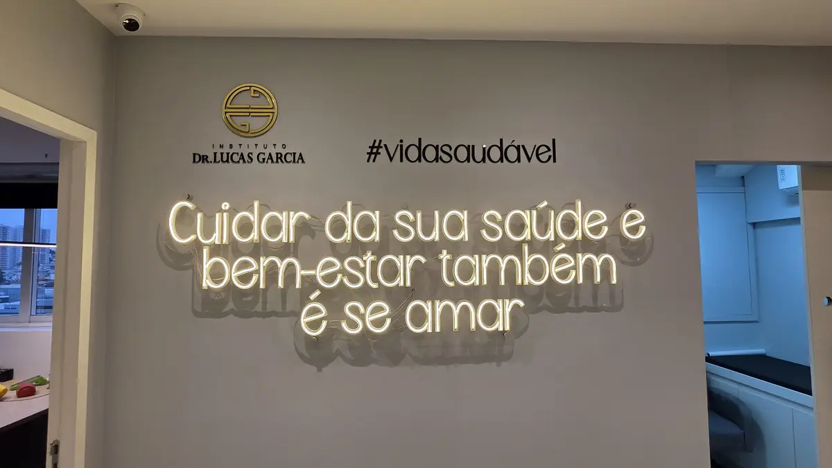 Letreiro luminoso com a frase cuidar da sua saúde e bem-estar também é se amar na parede da clínica