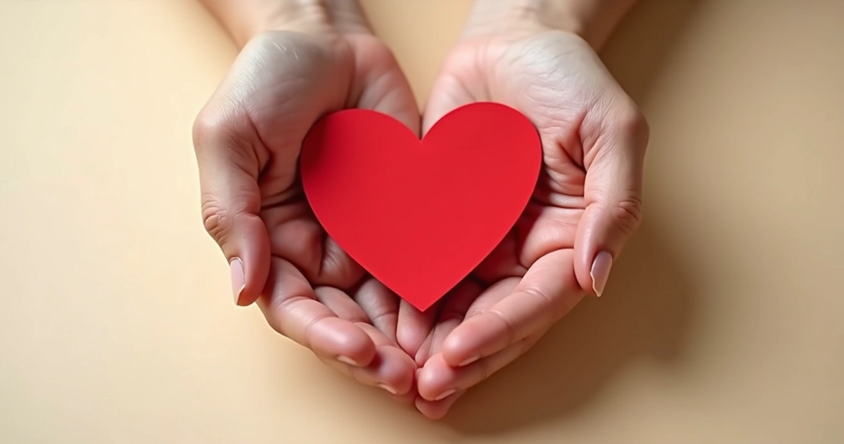 Manos abrazando un corazón de papel sobre fondo claro 