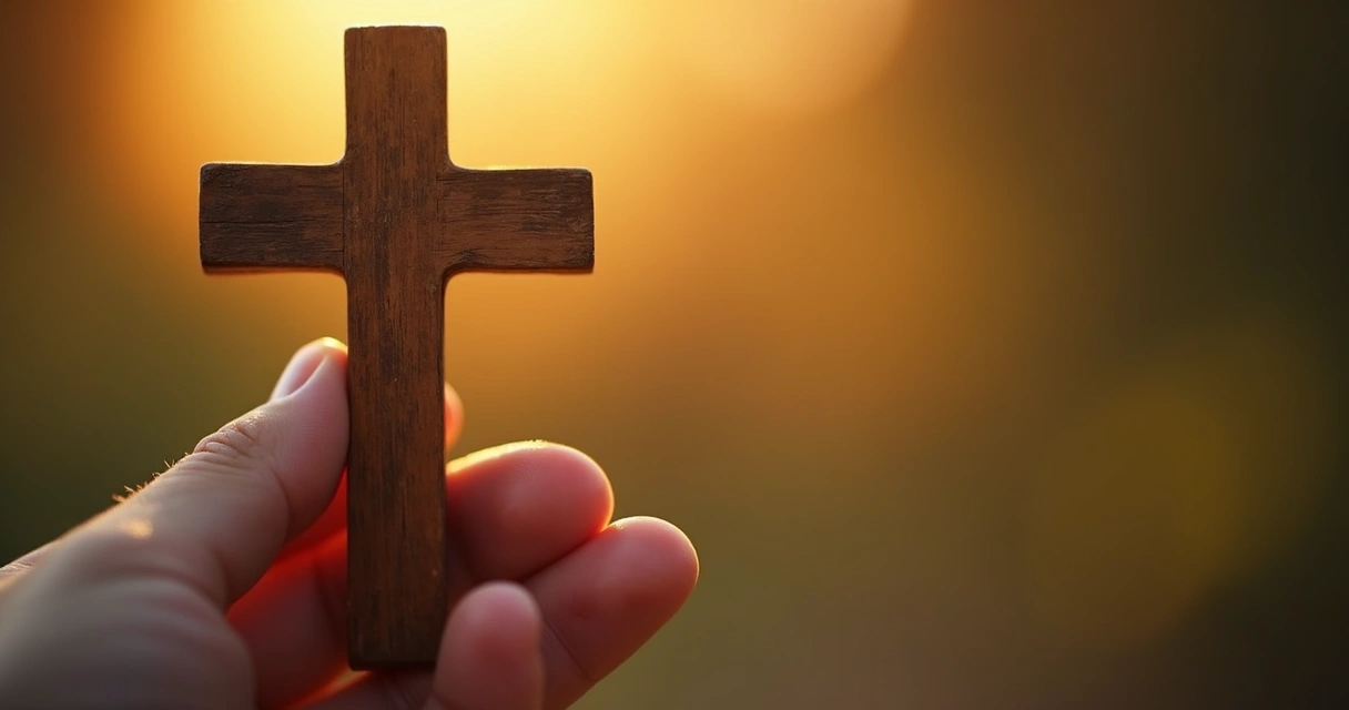 Mão segurando crucifixo de madeira com fundo desfocado 