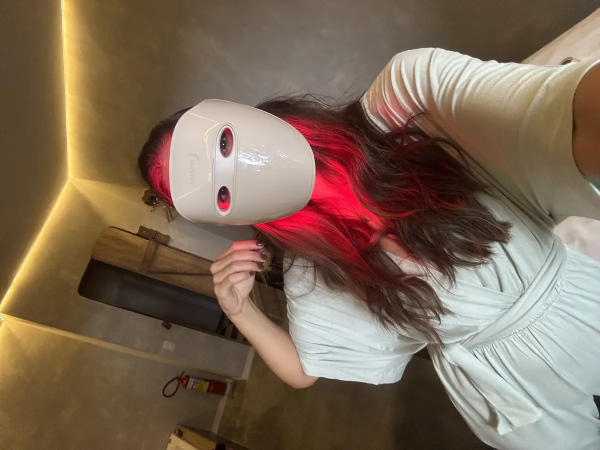 Pessoa usando máscara facial de LED vermelha em ambiente interno com parede cinza