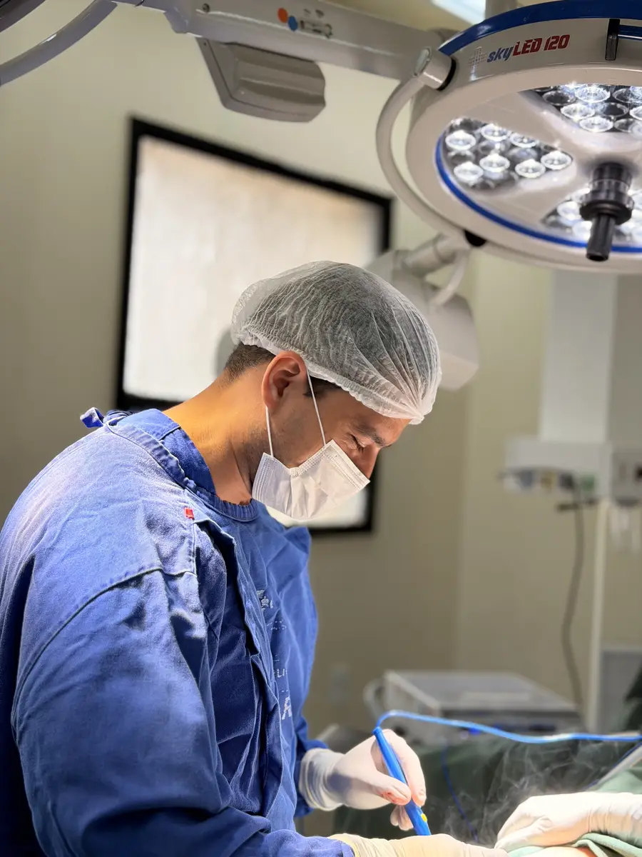 Médico cirurgião vascular realizando procedimento cirúrgico com roupas e máscaras de proteção