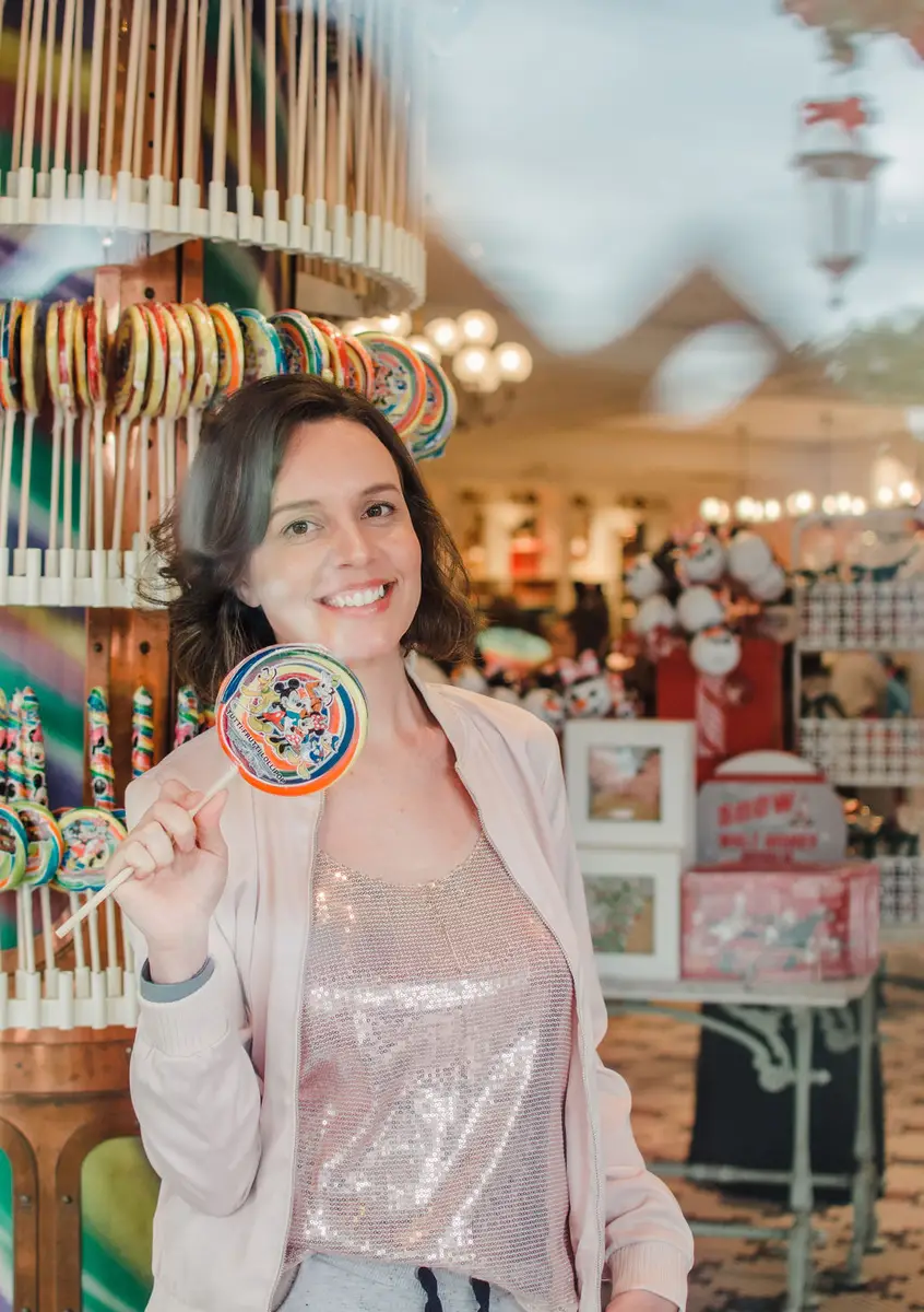 Mulher sorridente segurando pirulito colorido com personagens da Disney em loja temática