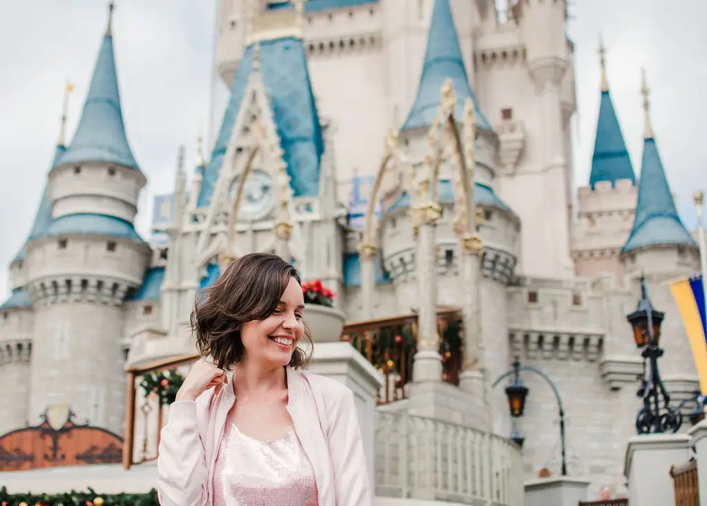 Mulher sorrindo em frente ao castelo da Cinderela na Disney