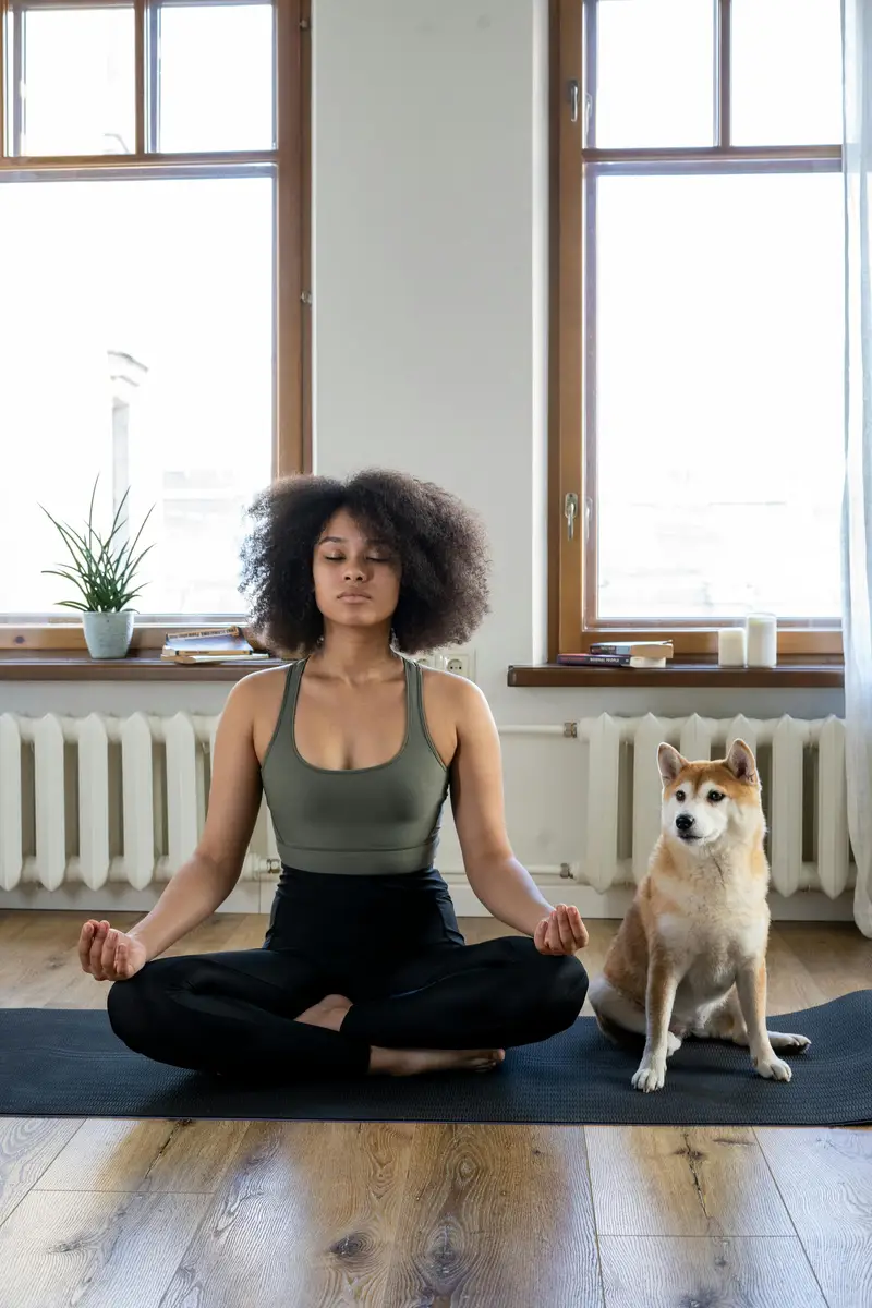 Mulher meditando sentada no chão com um cachorro ao lado