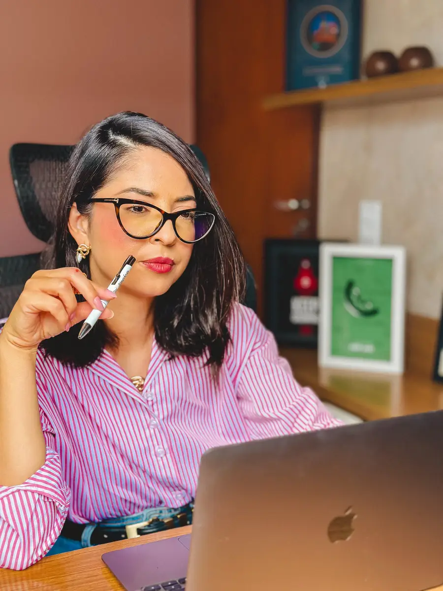 Mulher com blusa listrada observando atentamente a tela do computador