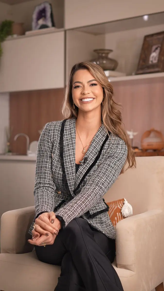 Mulher sorridente sentada em poltrona em ambiente moderno e acolhedor