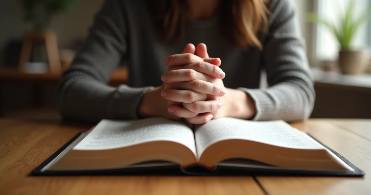 Pessoa de mãos dadas orando com uma Bíblia aberta sobre a mesa
