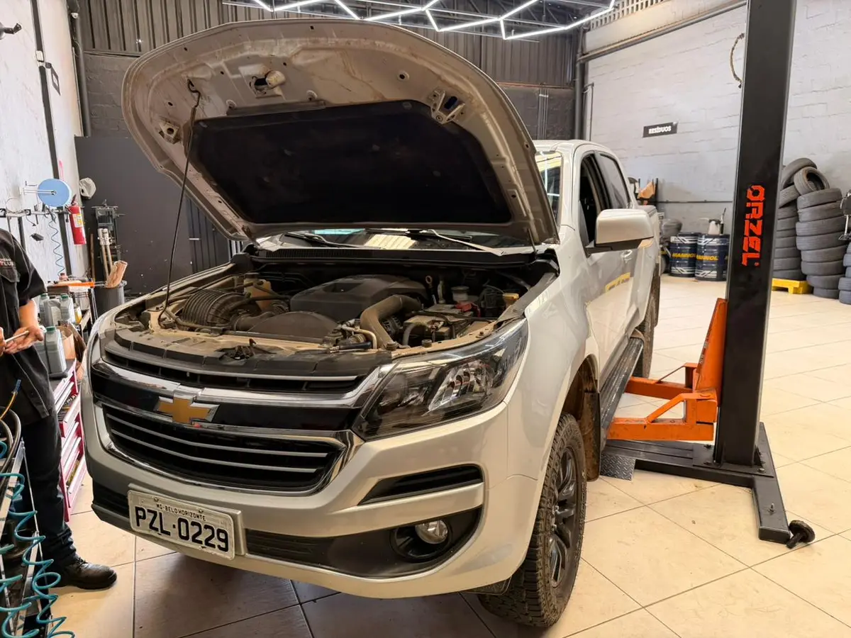 Pickup branca com capô aberto passando por revisão na oficina Megap Lub Auto Center