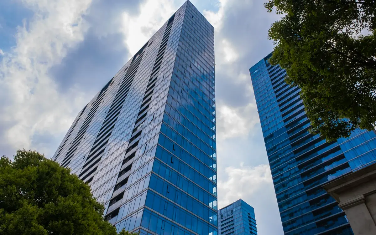 Prédios comerciais modernos com fachadas de vidro refletindo o céu nublado