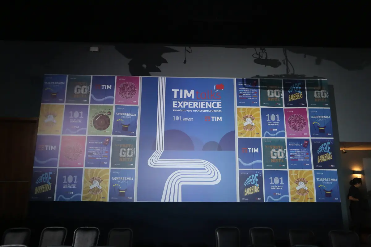 Projeção de slides da TIM Talks Experience em parede com cores azul, amarelo, roxo e rosa