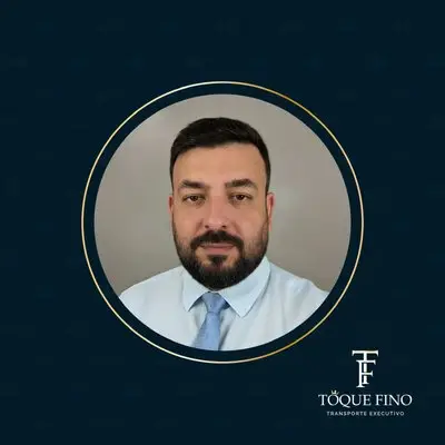 Retrato de homem com terno, camisa branca e gravata azul clara em fundo cinza