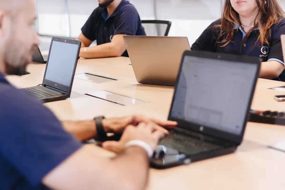 Equipe de profissionais usando laptops em reunião ao redor de mesa de escritório
