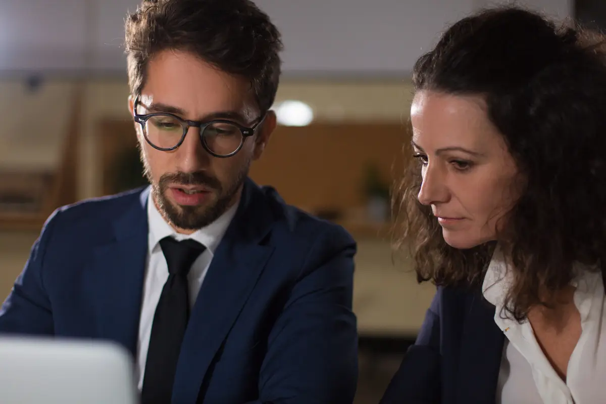 Homem e mulher em uma reunião de negócios olhando para um laptop.