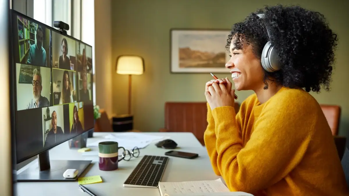 Mulher com fones de ouvido sorrindo durante reunião virtual no computador