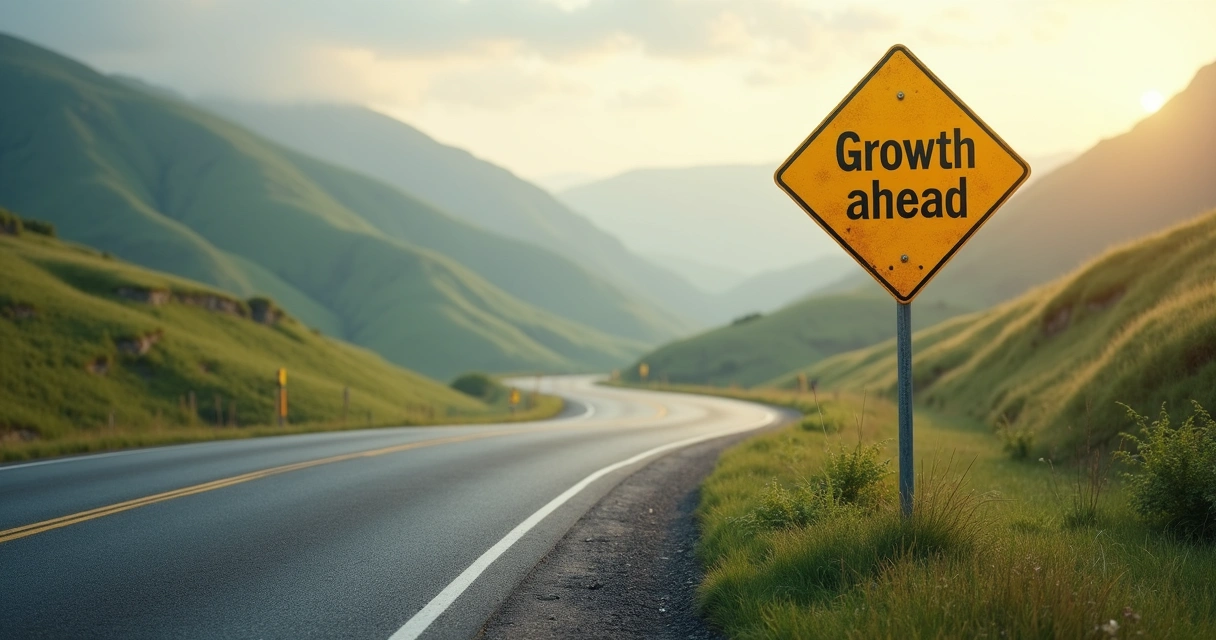 Sign on a road labeled Growth ahead with a mountain backdrop 
