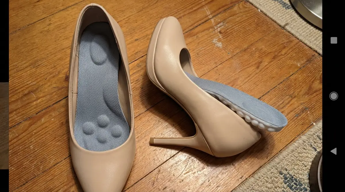 Sapatos de salto alto bege com palmilhas ortopédicas Impacty colocadas dentro deles sobre piso de madeira