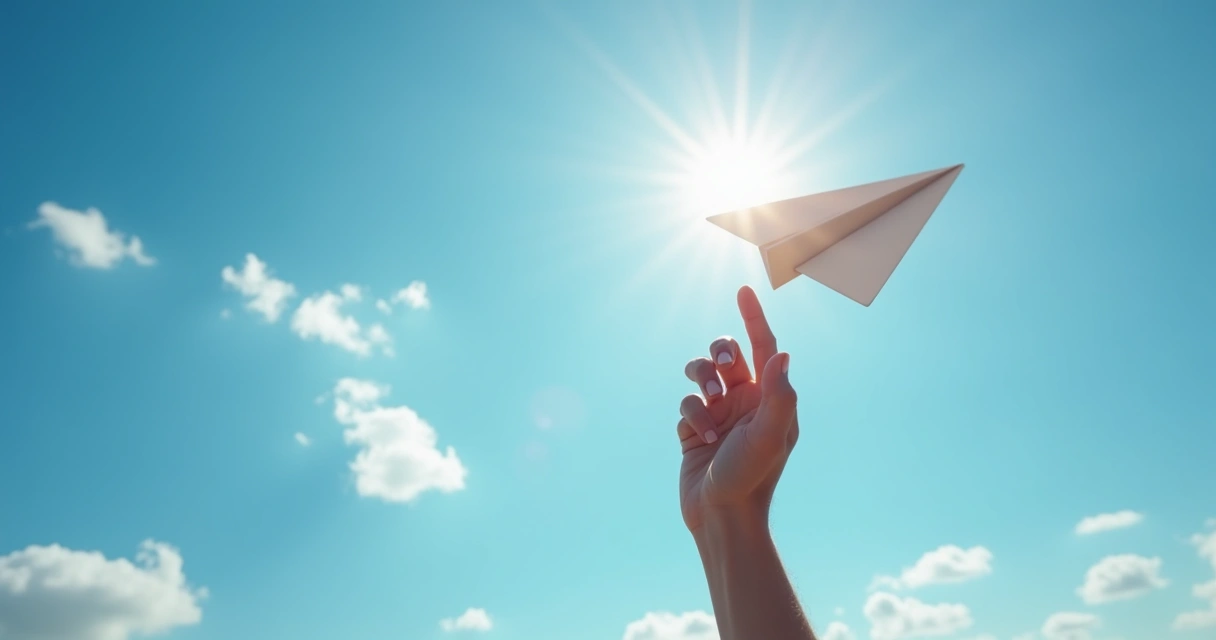 Mano soltando un avión de papel hacia el cielo azul