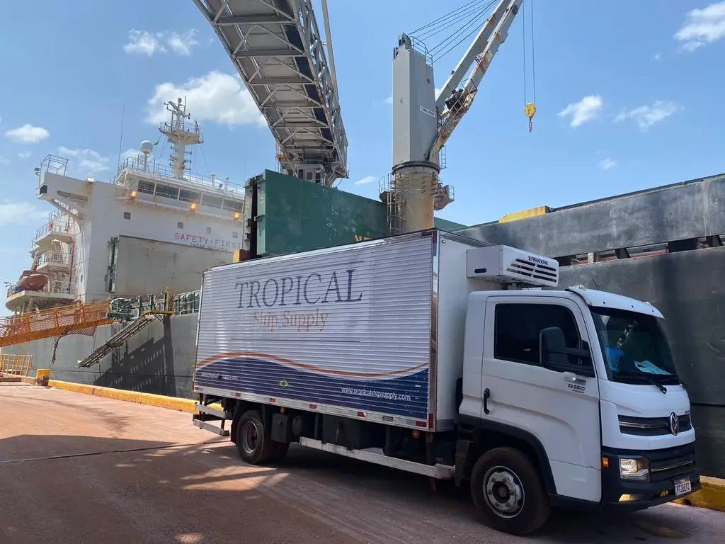 Tropical Ship Supply delivery truck parked near a cargo ship at port
