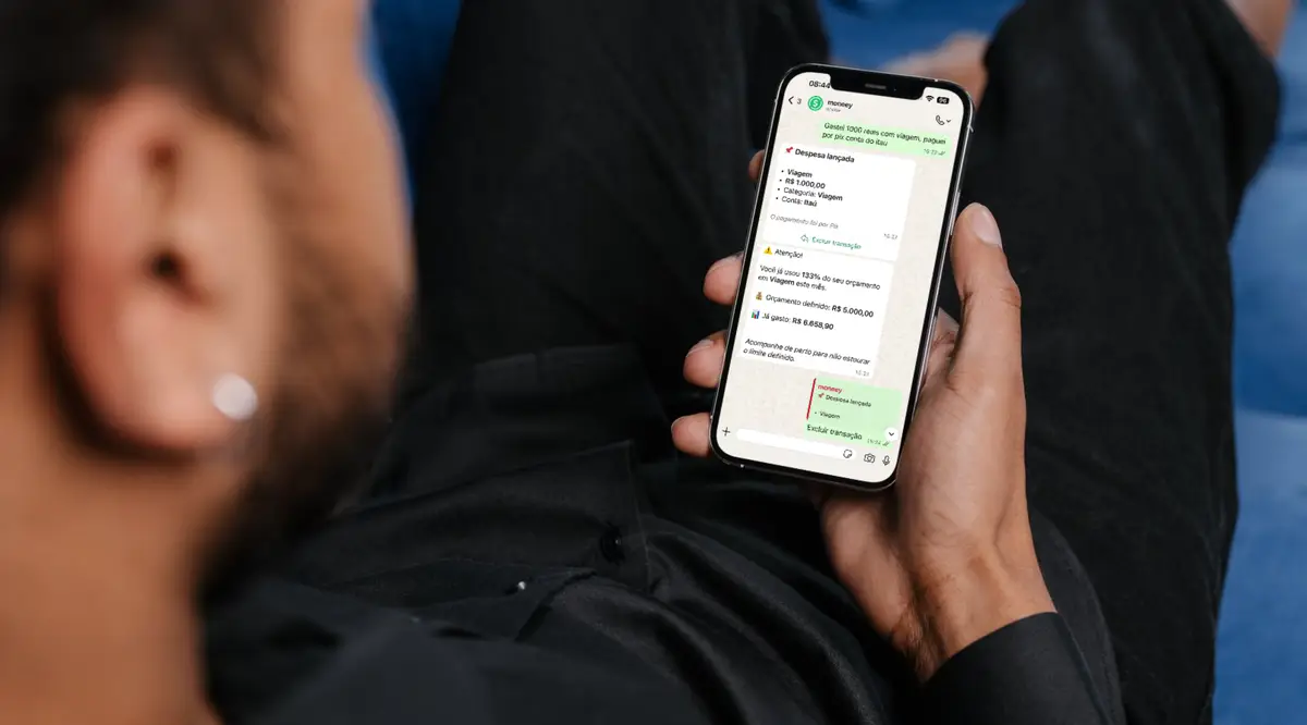 Pessoa segurando celular exibindo conversa no WhatsApp com assistente financeiro moneey