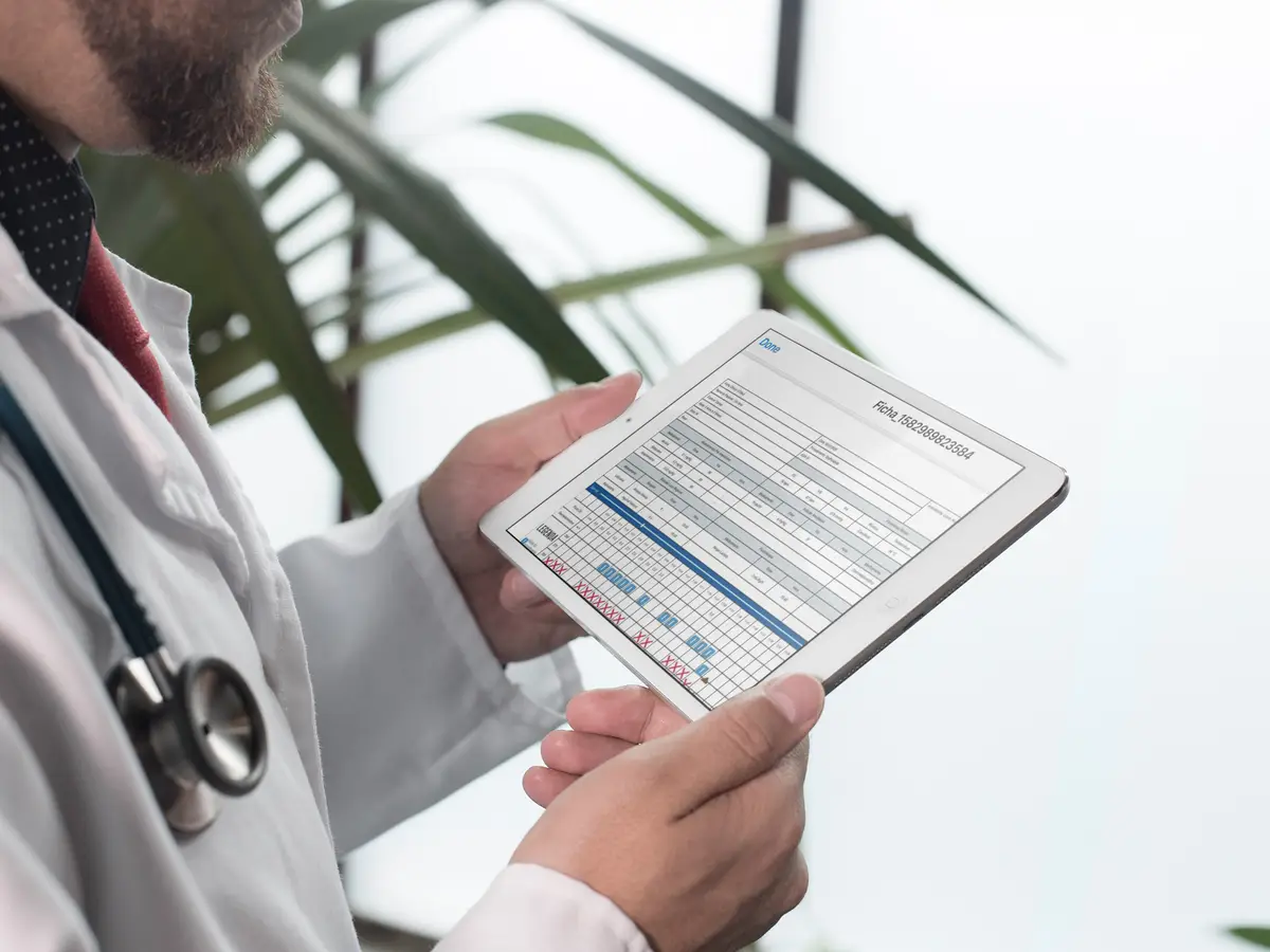 Médico veterinário segurando tablet com ficha anestésica digital aberta.