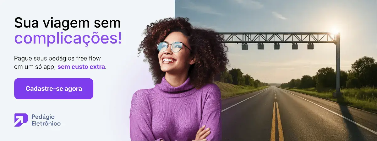 Mulher sorridente com blusa roxa e óculos ao lado de rodovia com pórtico eletrônico ao fundo